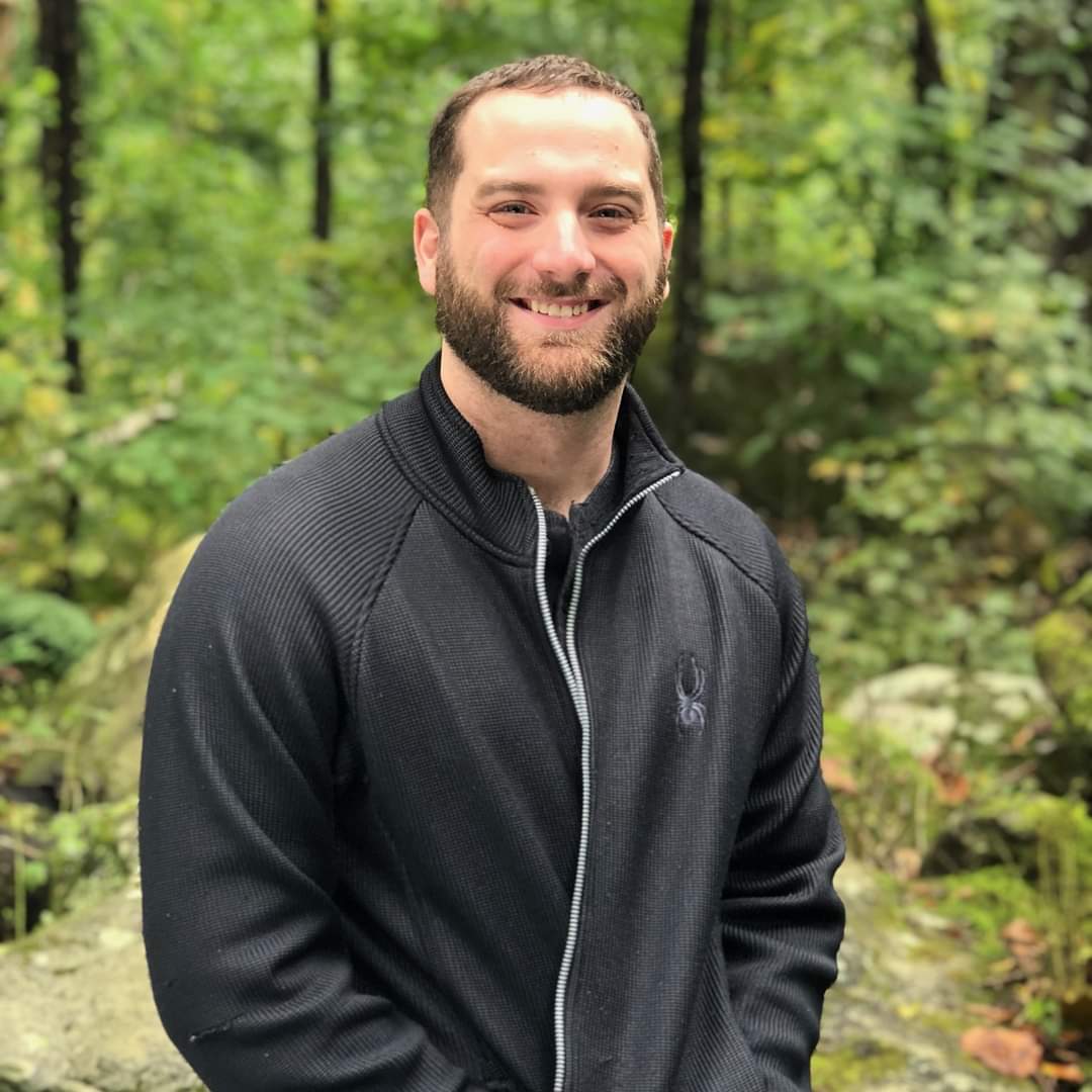 Andrew Miller, smiling in the woods